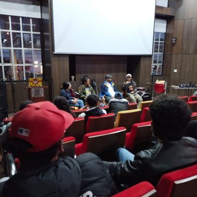 Panel of young musicians talking to a seated audience in an auditorium